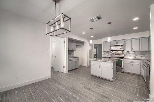 kitchen with visible vents, decorative backsplash, a center island, gray cabinets, and stainless steel appliances