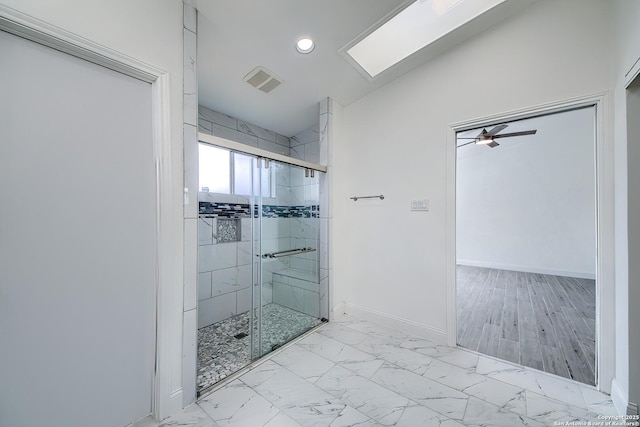 bathroom featuring vaulted ceiling with skylight, visible vents, baseboards, marble finish floor, and a shower stall