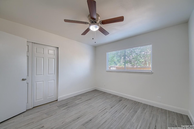 unfurnished bedroom with light wood-type flooring, a closet, baseboards, and a ceiling fan