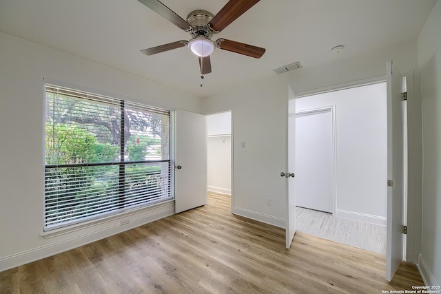 unfurnished bedroom featuring a ceiling fan, visible vents, baseboards, and wood finished floors