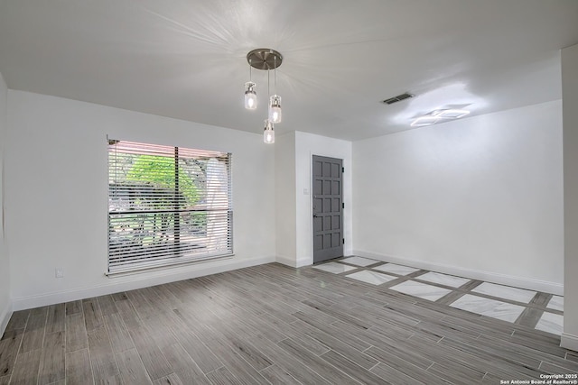 unfurnished room with visible vents, baseboards, and wood finished floors