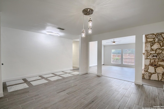 spare room with baseboards, ceiling fan, visible vents, and wood tiled floor