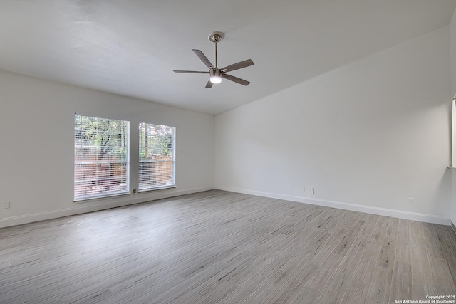 spare room with ceiling fan, light wood-style flooring, and baseboards