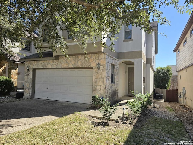 view of front of house featuring an attached garage, driveway, stone siding, and stucco siding