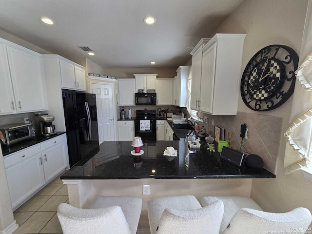 kitchen with tasteful backsplash, visible vents, light tile patterned flooring, a peninsula, and black appliances