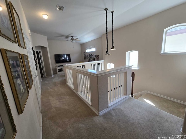 corridor featuring arched walkways, carpet, visible vents, an upstairs landing, and baseboards