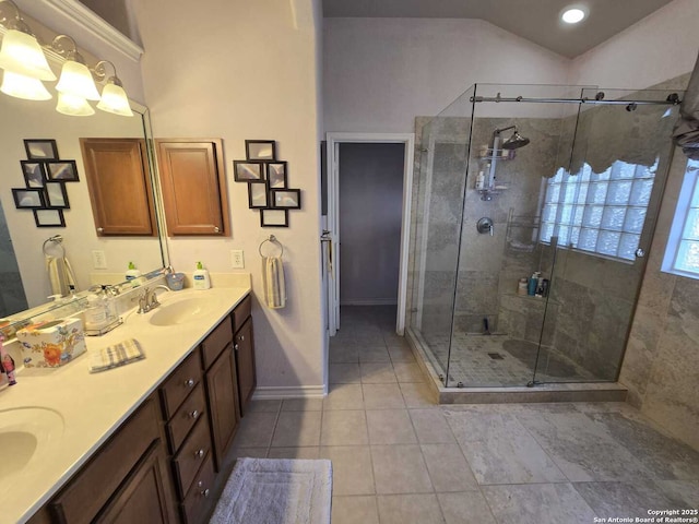 full bath with double vanity, a shower stall, vaulted ceiling, and a sink