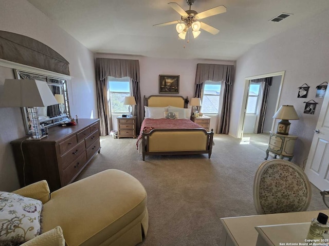 bedroom with light colored carpet, visible vents, and multiple windows