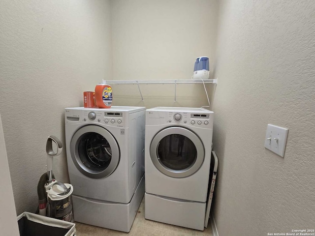 washroom featuring a textured wall, laundry area, separate washer and dryer, and light tile patterned flooring