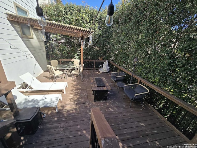 wooden terrace featuring a fire pit, outdoor dining area, and a pergola