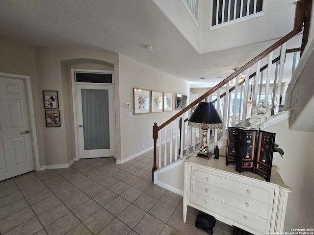 tiled entrance foyer with stairs and baseboards