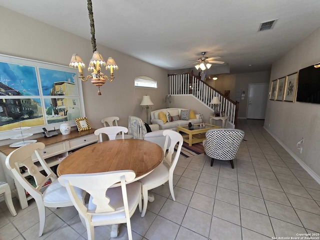 dining space featuring light tile patterned floors, ceiling fan with notable chandelier, visible vents, baseboards, and stairs