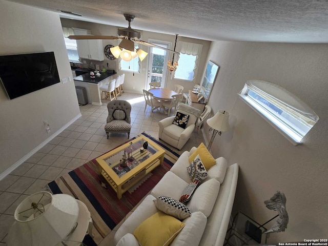 living room with a textured ceiling, light tile patterned flooring, a ceiling fan, and baseboards