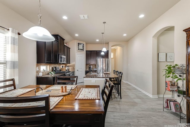 dining room featuring arched walkways, recessed lighting, visible vents, light wood-type flooring, and baseboards