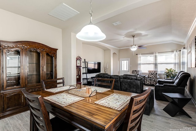 dining space featuring arched walkways, visible vents, light wood-style flooring, ornamental molding, and ceiling fan