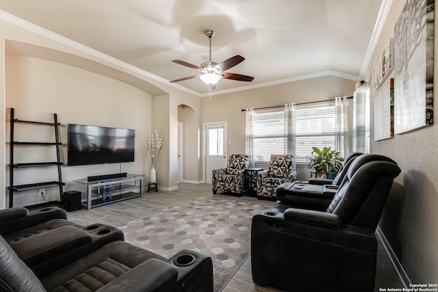 living room with arched walkways, lofted ceiling, a ceiling fan, baseboards, and ornamental molding