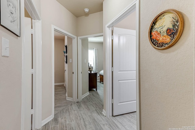 hallway with light wood-style flooring and baseboards