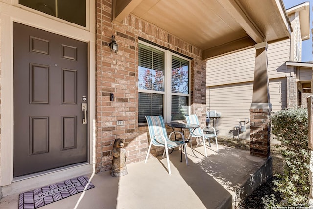 entrance to property with a porch and brick siding