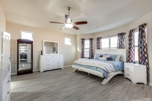 bedroom featuring a ceiling fan, light wood-style flooring, and baseboards