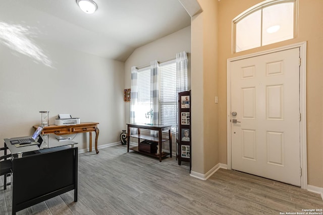 entryway featuring lofted ceiling, wood finished floors, and baseboards