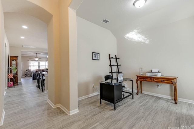 office featuring light wood-style floors, visible vents, arched walkways, and baseboards