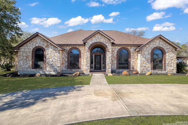 french country style house with a shingled roof and a front yard