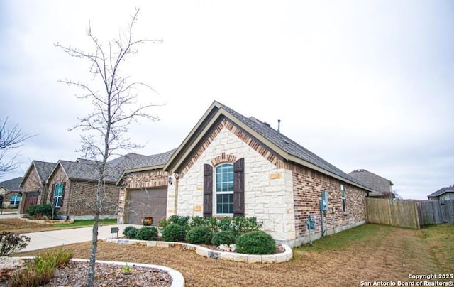 view of home's exterior featuring a garage, stone siding, fence, and concrete driveway