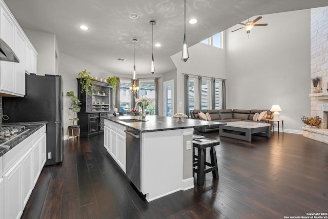 kitchen featuring dark wood finished floors, a fireplace, open floor plan, a sink, and dishwasher