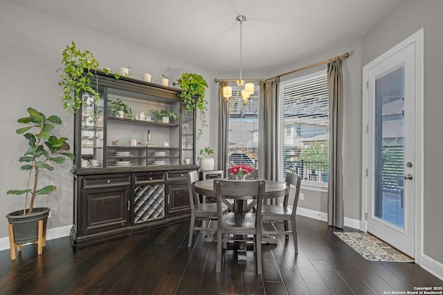 dining room with dark wood-style floors, baseboards, and an inviting chandelier