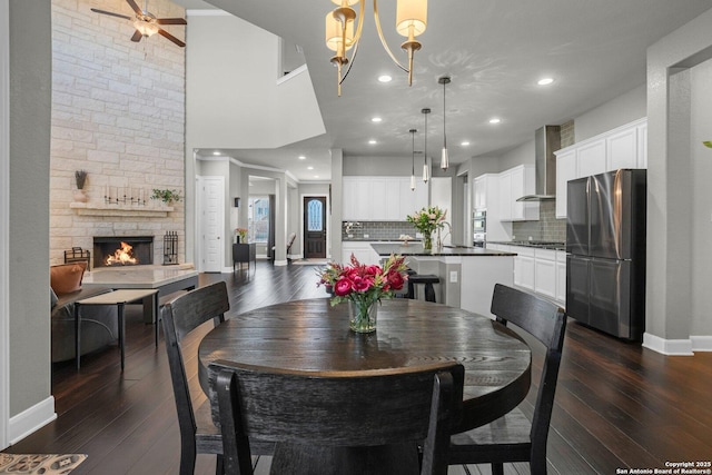 dining area with a fireplace, baseboards, dark wood-style flooring, and recessed lighting