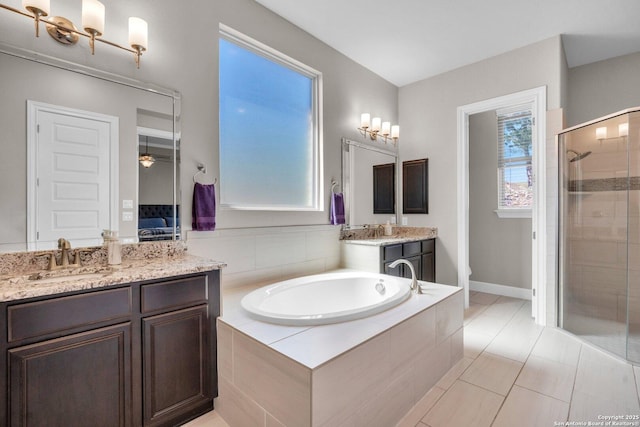 bathroom with a garden tub, two vanities, toilet, a stall shower, and a sink