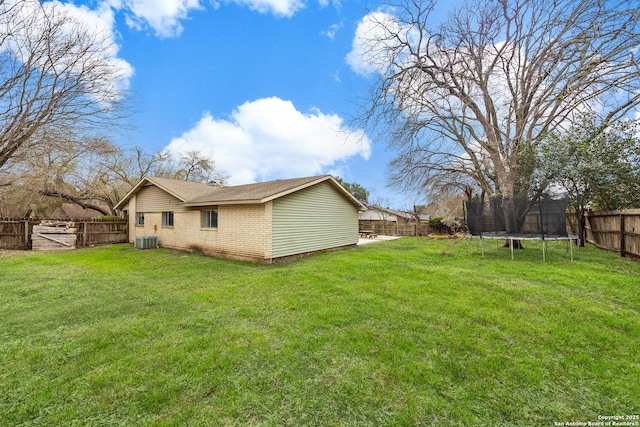 view of yard with central air condition unit, a fenced backyard, and a trampoline