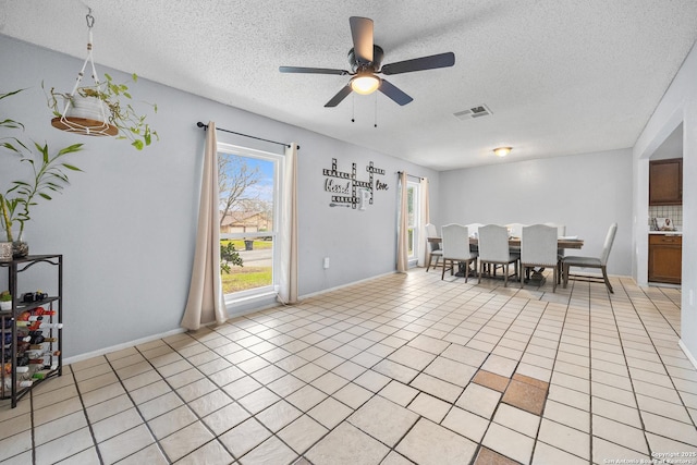 dining space with ceiling fan, a textured ceiling, light tile patterned flooring, and visible vents