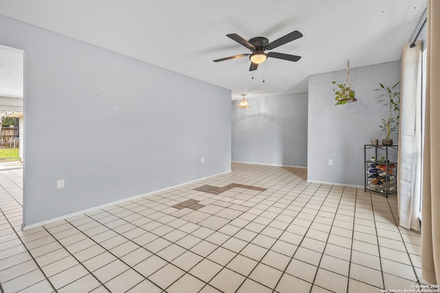 spare room featuring a ceiling fan, light tile patterned flooring, and a textured ceiling