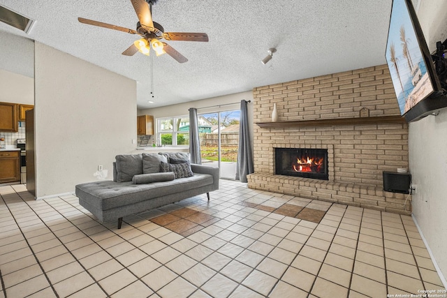 living area with a textured ceiling, light tile patterned flooring, a fireplace, and a ceiling fan