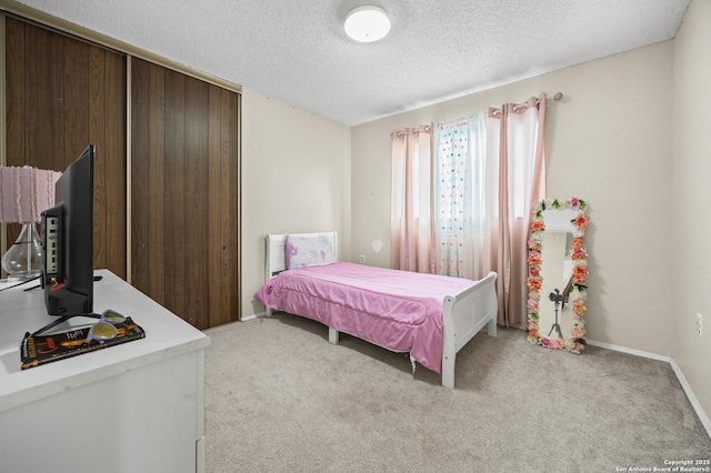 bedroom featuring light carpet, a textured ceiling, and baseboards