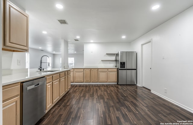 kitchen featuring stainless steel appliances, a peninsula, a sink, visible vents, and light brown cabinetry