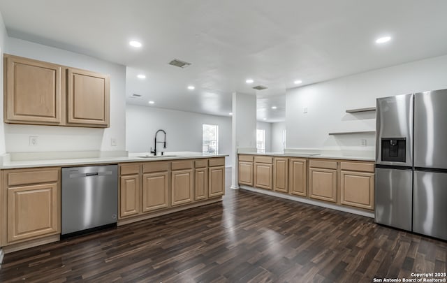 kitchen featuring visible vents, a peninsula, stainless steel appliances, light brown cabinets, and a sink