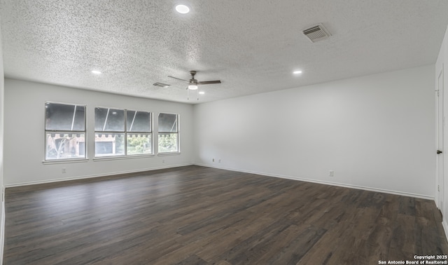 spare room featuring dark wood-style flooring, visible vents, a ceiling fan, a textured ceiling, and baseboards