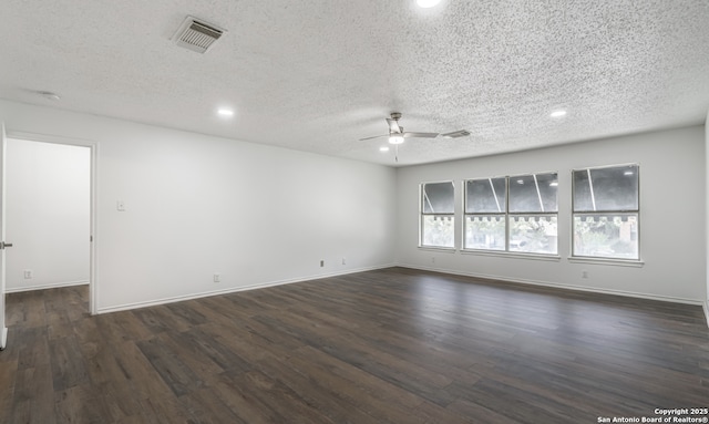 spare room featuring dark wood-style flooring, visible vents, ceiling fan, a textured ceiling, and baseboards