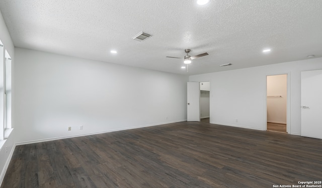 unfurnished bedroom with a spacious closet, visible vents, dark wood finished floors, and a textured ceiling