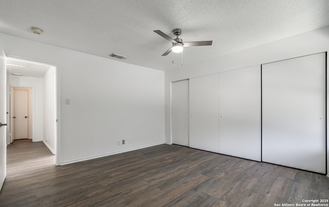 unfurnished bedroom featuring a closet, a textured ceiling, visible vents, and wood finished floors