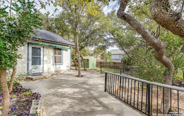 view of patio with a storage unit, fence, and an outbuilding