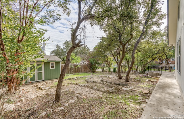 view of yard featuring an outbuilding, fence, and a storage unit