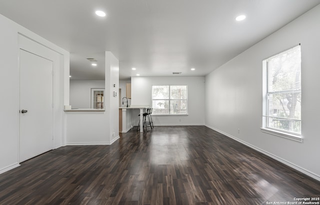 unfurnished living room featuring recessed lighting, dark wood finished floors, and baseboards