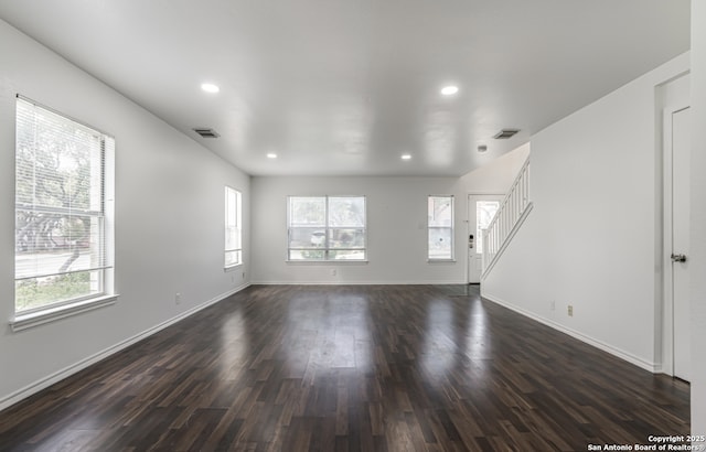 unfurnished living room with dark wood-style flooring, visible vents, and baseboards