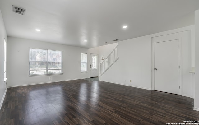 unfurnished living room featuring stairway, baseboards, visible vents, and dark wood finished floors