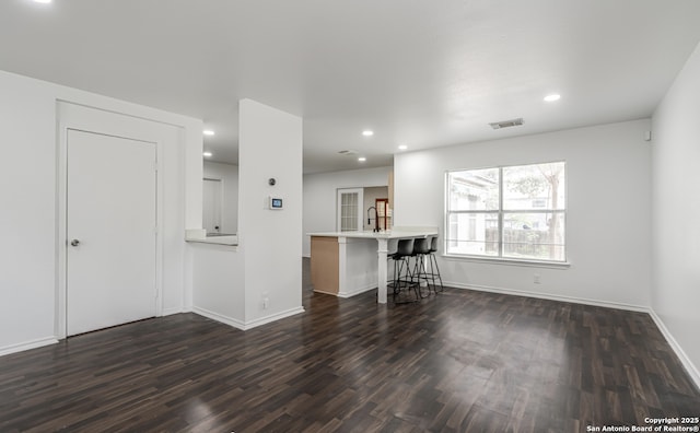 unfurnished living room featuring dark wood-style floors, baseboards, visible vents, and recessed lighting