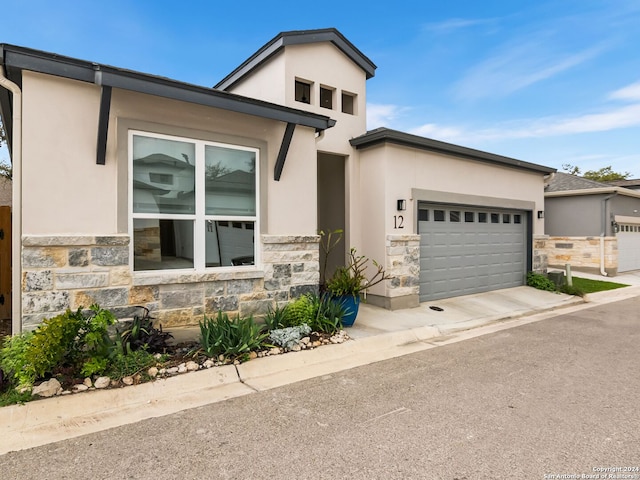 view of front of house featuring stone siding, an attached garage, and stucco siding