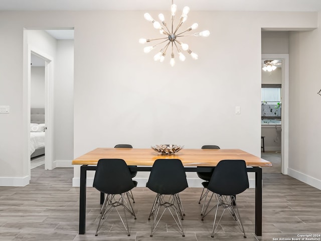 dining room featuring light wood-style flooring, baseboards, and an inviting chandelier